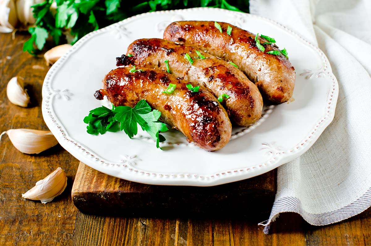 Three Italian sausages on a white plate. 